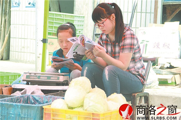 商州區(qū)楊斜鎮(zhèn)集市上，南思佳和妹妹在幫父母賣菜，閑暇之余，她們會拿起課外讀物翻一翻。在這個假期里，她們呆的最多的地方就是這個菜攤。